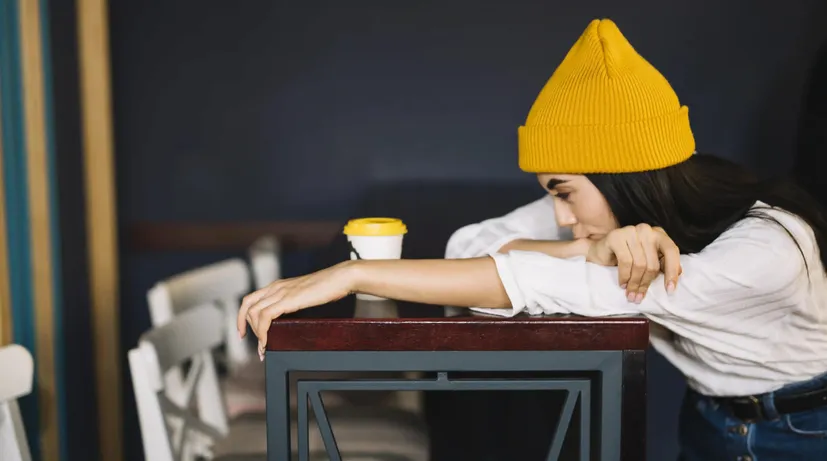 dívka sedí stranou v kavárně, nemá chuť se s někým bavit