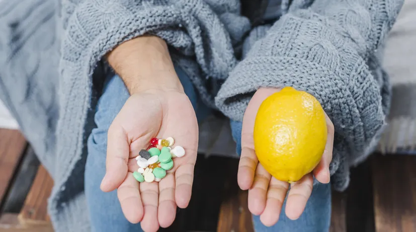 žena v jedné ruce má vitamíny v tabletách, ve druhé citron