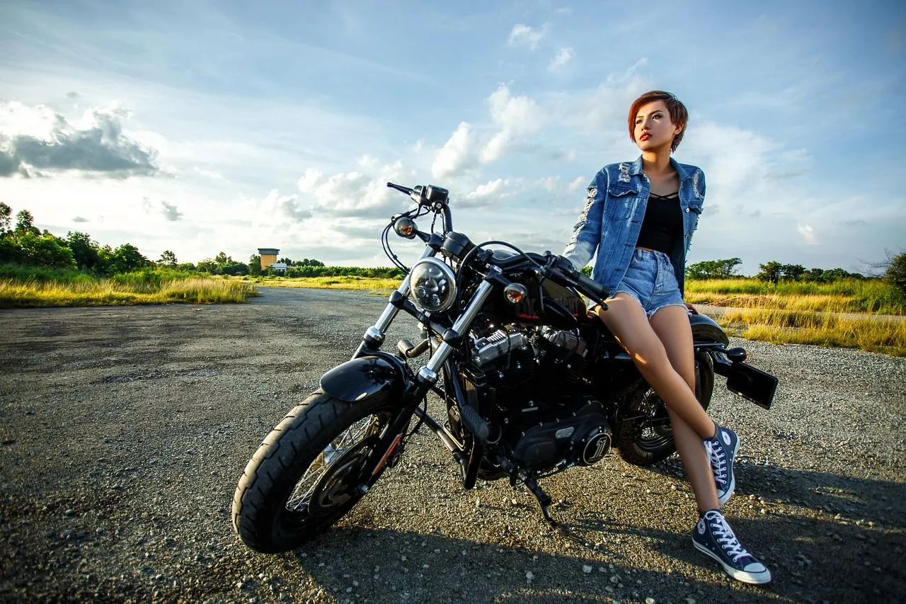 dívka opřená o silnou motorku, za ní pole
