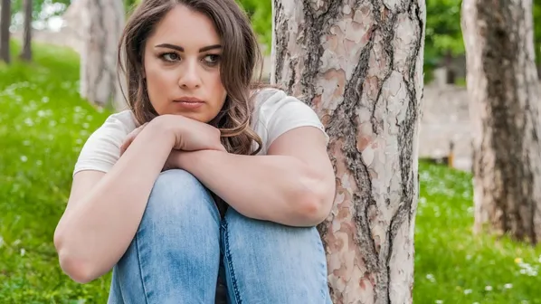 ubrečená dívka sedí v parku u stromu